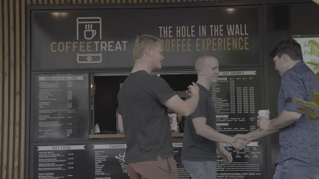 Customers ordering at a Coffee Treat hole-in-the-wall counter